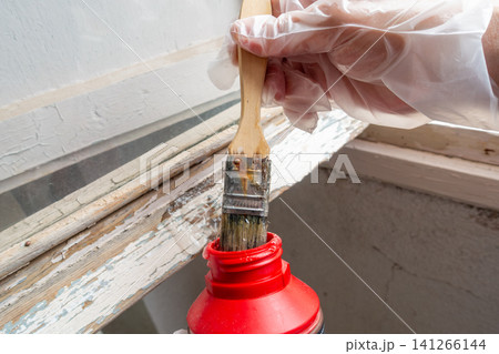 Hand Dipping Brush into Paint Remover Gel Before Window Restoration Hand Dipping Brush into Paint Remover Gel Before Window Restoration 141266144