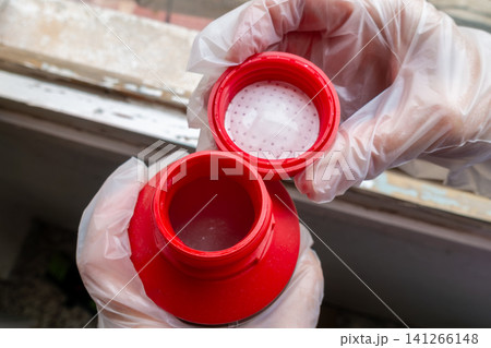 Hands Wearing Protective Gloves Holding Paint Remover Gel Bottle Hands Wearing Protective Gloves Holding Paint Remover Gel Bottle 141266148