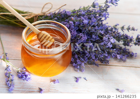 Honey jar with dipper and fresh lavender flowers Honey jar with dipper and fresh lavender flowers 141266235