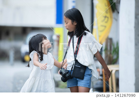 一眼レフカメラを持ってお散歩中に変顔をして笑い合う女の子2人 一眼レフカメラを持ってお散歩中に変顔をして笑い合う女の子2人 141267090