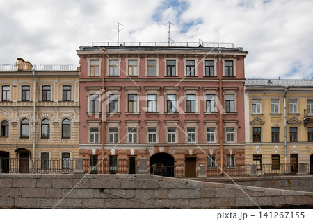 Beautiful buildings line the canal in St. Petersburg, displaying distinct architectural styles and colors under a partly cloudy sky, evoking history. Beautiful buildings line the canal in St. Petersburg, displaying distinct architectural styles and colors under a partly cloudy sky, evoking history. 141267155