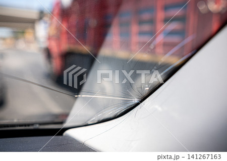 Windshield shows a noticeable crack while stopped in traffic, accompanied by a large truck in the background under clear skies. Windshield shows a noticeable crack while stopped in traffic, accompanied by a large truck in the background under clear skies. 141267163