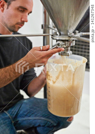 Brewery, man and tap on machine with craft beer for sample, alcohol test or production process in factory. Industrial industry, worker hands or working in distillery with jug for brewing in warehouse Brewery, man and tap on machine with craft beer for sample, alcohol test or production process in factory. Industrial industry, worker hands or working in distillery with jug for brewing in warehouse 141267348