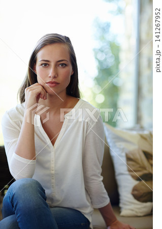 Woman, portrait and confident in home on sofa with serious face for pensive mood or quiet contemplation and inner thoughts. Female person, couch and thinking or wondering in living room and calm. Woman, portrait and confident in home on sofa with serious face for pensive mood or quiet contemplation and inner thoughts. Female person, couch and thinking or wondering in living room and calm. 141267952