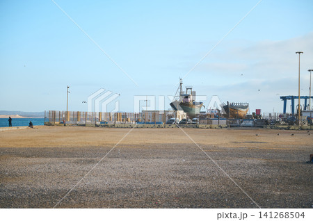 Fishing boats on dry dock near Essaouira harbor in Morocco with tourists and authentic coastal atmosphere 141268504