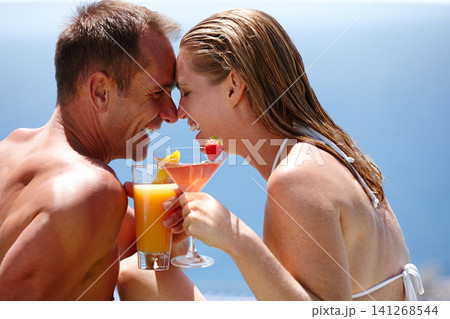 Couple, happy and toast with cocktail by swimming pool with care, vacation and love in summer. Man, woman and smile by ocean with drink, alcohol or outdoor in sunshine, water and holiday in Naples Couple, happy and toast with cocktail by swimming pool with care, vacation and love in summer. Man, woman and smile by ocean with drink, alcohol or outdoor in sunshine, water and holiday in Naples 141268544