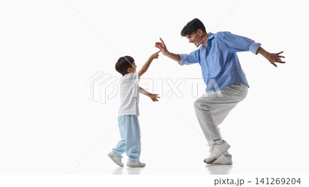 Father and son playing and reaching toward each other in studio. Father and son playing and reaching toward each other in studio. 141269204