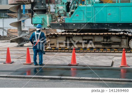 建設現場の警備員と大型穴掘り機 建設現場の警備員と大型穴掘り機 141269460