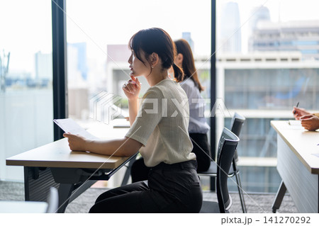 窓の外を眺めながら資料を読む女性 窓の外を眺めながら資料を読む女性 141270292