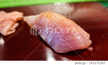 close up of Japanese tuna (toro) nigiri sushi served on a glossy dark plate with sweet pink pickled ginger on the side and copy space close up of Japanese tuna (toro) nigiri sushi served on a glossy dark plate with sweet pink pickled ginger on the side and copy space 141271267