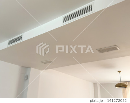 A recessed linear air diffuser of a ducted air conditioner in a ceiling soffit. Modern HVAC ventilation and cooling A recessed linear air diffuser of a ducted air conditioner in a ceiling soffit. Modern HVAC ventilation and cooling 141272032