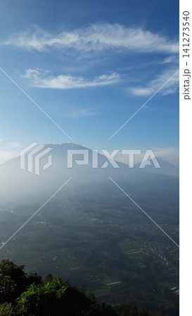 Misty mountain peaks rise above lush green forests Misty mountain peaks rise above lush green forests 141273540