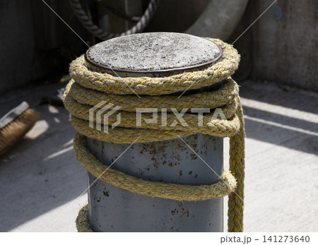 Yellow braided rope wrapped around a mooring bollard at a marina, conveying recreation on the water with a nautical vibe. Yellow braided rope wrapped around a mooring bollard at a marina, conveying recreation on the water with a nautical vibe. 141273640