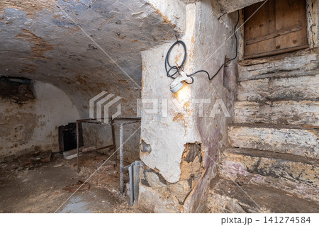 Old stone basement featuring rugged stairs and warm light bulb Old stone basement featuring rugged stairs and warm light bulb 141274584