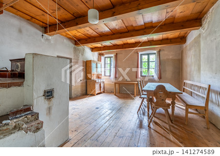 Old cottage interior featuring wooden furniture and historical stove Old cottage interior featuring wooden furniture and historical stove 141274589