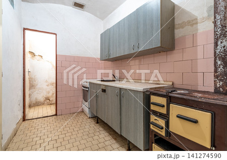 Abandoned kitchen showing old appliances and worn pink tiles 141274590