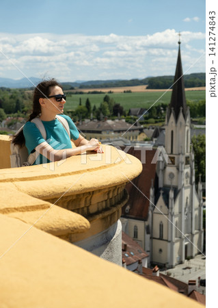 Young woman tourist with backpack enjoying panorama of the old Austrian historical city. 141274843