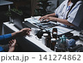 Two asian women doctors discuss meeting doctor's office medical clinic looking x-ray film consulting patient disease. Asian medical lab young women talking together discussing healthcare teamwork 141274862