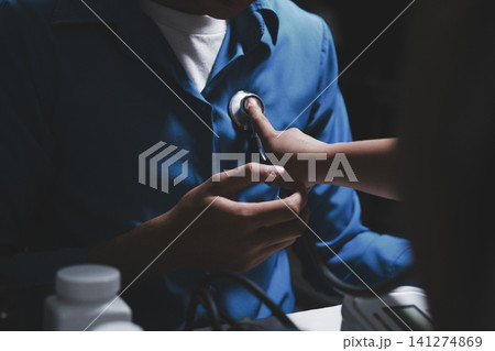 Doctor use stethoscope, checking up heart beat, auscultation in doctor office at hospital. Patient worker has to get medical checkup every year for her health or 141274869