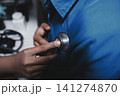 Doctor use stethoscope, checking up heart beat, auscultation in doctor office at hospital. Patient worker has to get medical checkup every year for her health or 141274870