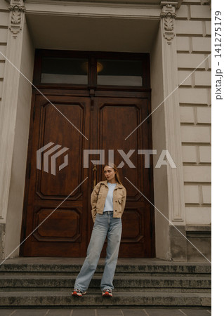 Girl with freckles stands in front of a large wooden door at a historical building during the day Girl with freckles stands in front of a large wooden door at a historical building during the day 141275179