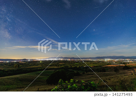 丸加高原から望む夜空に美しく輝く天の川と地平線の夜景を横切る一筋の流星 丸加高原から望む夜空に美しく輝く天の川と地平線の夜景を横切る一筋の流星 141275493