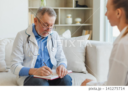 Senior man doctor examining young woman in doctor office or at home. Girl patient and doctor have consultation in hospital room. Medicine healthcare medical checkup. Visit to doctor Senior man doctor examining young woman in doctor office or at home. Girl patient and doctor have consultation in hospital room. Medicine healthcare medical checkup. Visit to doctor 141275714