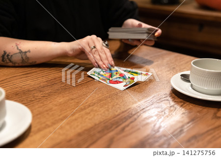 Tarot cards and fortune telling. Soothsayer predicting future with tarot cards. Unrecognizable mysterious fortuneteller holding tarot cards forecasting future for client. Future reading esoteric Tarot cards and fortune telling. Soothsayer predicting future with tarot cards. Unrecognizable mysterious fortuneteller holding tarot cards forecasting future for client. Future reading esoteric 141275756