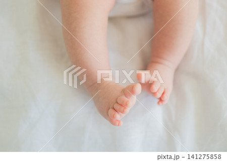 Tiny newborn infant baby feet and toes on white background. Soft newborn baby foot legs under the white blanket. Close up of infant barefeet. Maternity tenderness parenthood birthday. Happy Family 141275858