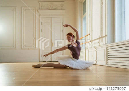 Young ballerina in tutu skirt stretching practicing ballet positions dancing in dance class. Young classical dancer woman in dance studio. Ballet class training Ballet school concept Young ballerina in tutu skirt stretching practicing ballet positions dancing in dance class. Young classical dancer woman in dance studio. Ballet class training Ballet school concept 141275907