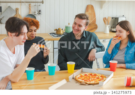 Home party. Overjoyed diverse friends eating ordered pizza for home party. Happy group multiracial young buddies enjoying spending free weekend time together having fun laughing joking communicating Home party. Overjoyed diverse friends eating ordered pizza for home party. Happy group multiracial young buddies enjoying spending free weekend time together having fun laughing joking communicating 141275973