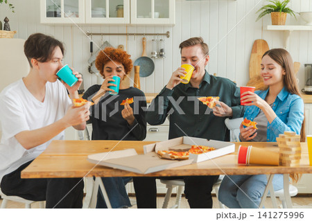 Home party. Friends spending time together having fun laughing communicating at home. Happy diverse group eating pizza drinking beer or lemonade. Mixed race young buddies best friends enjoying weekend 141275996