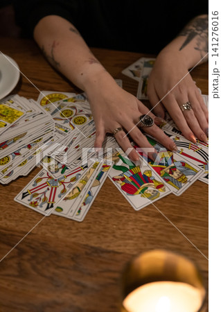 Tarot cards and fortune telling. Soothsayer predicting future with tarot cards. Unrecognizable mysterious fortuneteller holding tarot cards forecasting future for client. Future reading esoteric Tarot cards and fortune telling. Soothsayer predicting future with tarot cards. Unrecognizable mysterious fortuneteller holding tarot cards forecasting future for client. Future reading esoteric 141276016