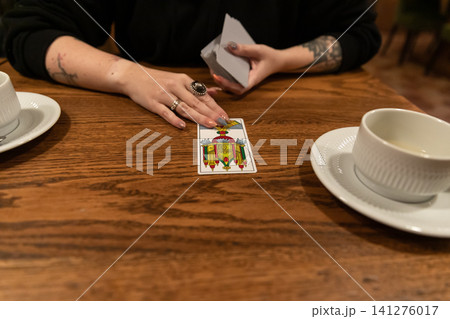 Tarot cards and fortune telling. Soothsayer predicting future with tarot cards. Unrecognizable mysterious fortuneteller holding tarot cards forecasting future for client. Future reading esoteric Tarot cards and fortune telling. Soothsayer predicting future with tarot cards. Unrecognizable mysterious fortuneteller holding tarot cards forecasting future for client. Future reading esoteric 141276017