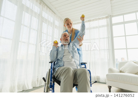 Support rehabilitation healthcare. Nurse helps old man patient in wheelchair picking up dumbbells. Paralyzed man in chair for people with disability doing sports exercise with nurse. Medical caregiver 141276052