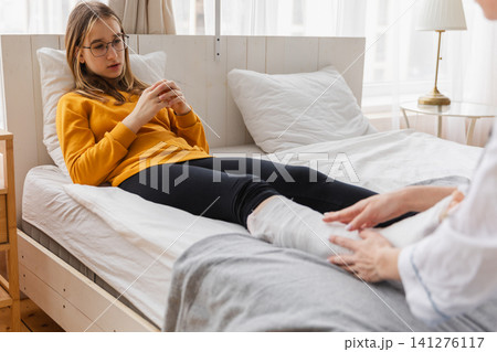 Girl with broken leg and doctor in clinic. Traumatologist orthopedist examines child leg in medical office. Doctor examining girl with medical plaster leg cast after broken ankle injury Rehabilitation Girl with broken leg and doctor in clinic. Traumatologist orthopedist examines child leg in medical office. Doctor examining girl with medical plaster leg cast after broken ankle injury Rehabilitation 141276117