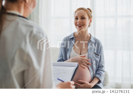 Female doctor examining pregnant woman in doctor office. Pregnant girl patient have consultation in hospital. Gynecologist doctor consulting patient about pregnancy. Visit to doctor medical checkup 141276131