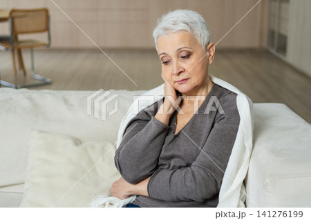 Sad tired ill sick lonely disappointed older senior woman sitting at home alone. Unhappy mature grandmother experiencing grief relative death bad news. Stressed elder lady suffering from loneliness 141276199