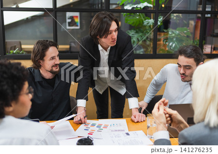 Teamwork brainstorm. Coworkers cooperating working together at office meeting. Colleagues discussing project ideas. Group of people in creative office discussing business. Young professional team 141276235