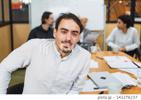 Portrait of team leader businessman in office, colleagues meeting in background. Confident business leader man sitting in office. Boss leader professional worker. Working process office life career 141276237