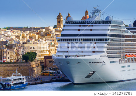VALLETTA, MALTA - NOVEMBER 12, 2018 - Panoramic night view of a coast line and the downtown of the city with different landmarks and MSC Magnifica cruise liner VALLETTA, MALTA - NOVEMBER 12, 2018 - Panoramic night view of a coast line and the downtown of the city with different landmarks and MSC Magnifica cruise liner 141278795