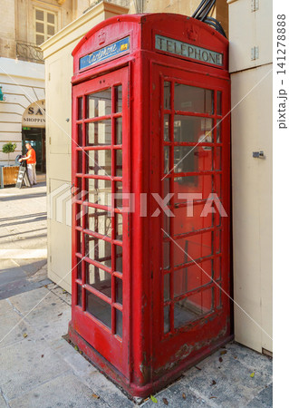 VALLETTA, MALTA - NOVEMBER 12, 2018 - Red phone booth with people on the background VALLETTA, MALTA - NOVEMBER 12, 2018 - Red phone booth with people on the background 141278888