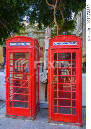VALLETTA, MALTA - NOVEMBER 12, 2018 - Red phone booth with people on the background VALLETTA, MALTA - NOVEMBER 12, 2018 - Red phone booth with people on the background 141278889