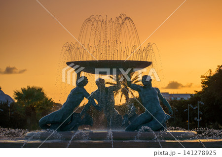 VALLETTA, MALTA - NOVEMBER 12, 2018 - The Triton Fountain In The City Gate Square with springs of water in the sunset VALLETTA, MALTA - NOVEMBER 12, 2018 - The Triton Fountain In The City Gate Square with springs of water in the sunset 141278925