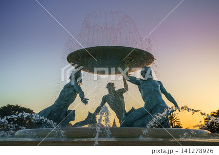 VALLETTA, MALTA - NOVEMBER 12, 2018 - The Triton Fountain In The City Gate Square with springs of water in the sunset VALLETTA, MALTA - NOVEMBER 12, 2018 - The Triton Fountain In The City Gate Square with springs of water in the sunset 141278926