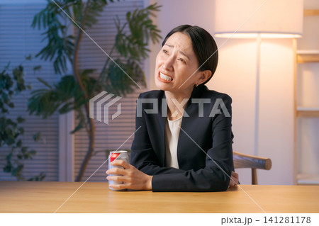 疲れた表情でお酒を飲む女性 疲れた表情でお酒を飲む女性 141281178