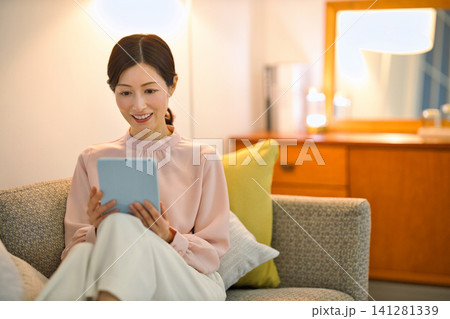 夜部屋でリラックスしてタブレットをを見る40代の女性 141281339