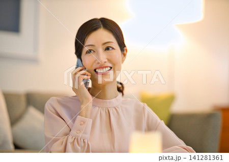 夜部屋でリラックスしてスマホを見る40代の女性 夜部屋でリラックスしてスマホを見る40代の女性 141281361