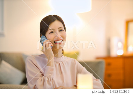 夜部屋でリラックスしてスマホを見る40代の女性 夜部屋でリラックスしてスマホを見る40代の女性 141281363