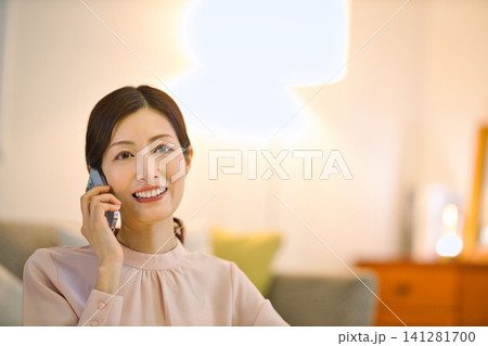 夜部屋でリラックスしてスマホを見る40代の女性 夜部屋でリラックスしてスマホを見る40代の女性 141281700